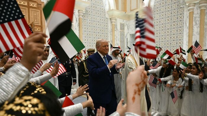 Gyerekek emirátusi és amerikai zászlókat lengetnek, amikor Donald Trump amerikai elnök megérkezik a Qasr Al-Watanba (a Nemzet Palotájába) Abu Dhabiban 2025. május 15-én. 