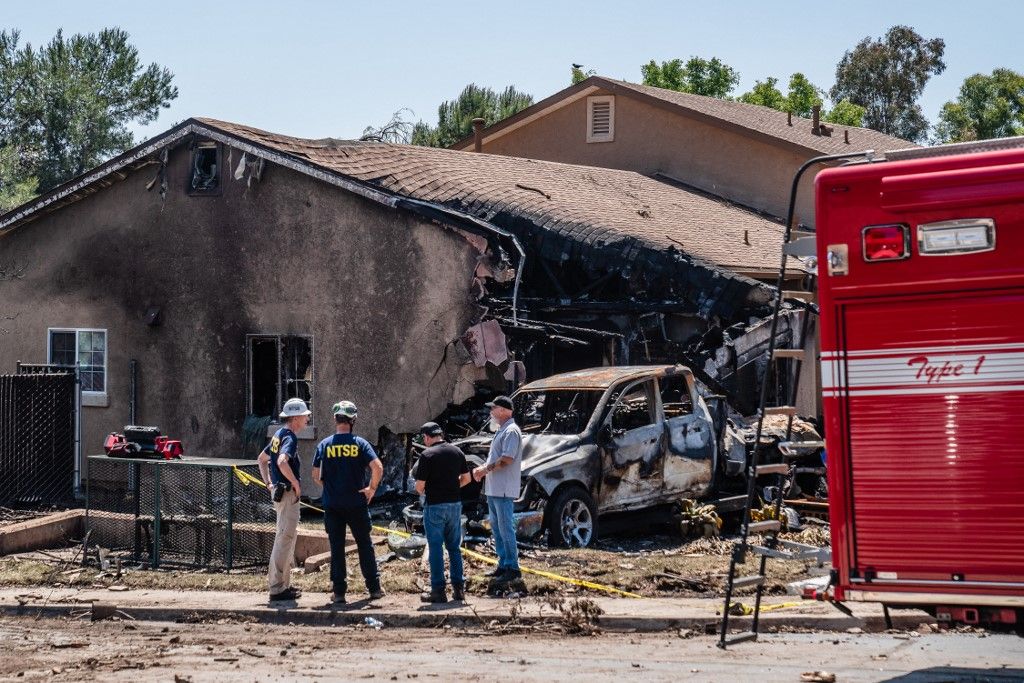 SAN DIEGO, CA - MAY 22: Members of the National Transportation Safety Board (NTSB) and the Federal Aviation Administration (FAA) stand in front of a damaged home after a small plane crashed into a neighborhood early this morning, setting homes and vehicles on fire on May 22, 2025 in San Diego, California. At least two people have died after a Cessna 550 aircraft crashed into a residential street in Murphy Canyon, causing evacuations after buildings were damaged. Ariana Drehsler/Getty Images/AFP (Photo by Ariana Drehsler / GETTY IMAGES NORTH AMERICA / Getty Images via AFP)