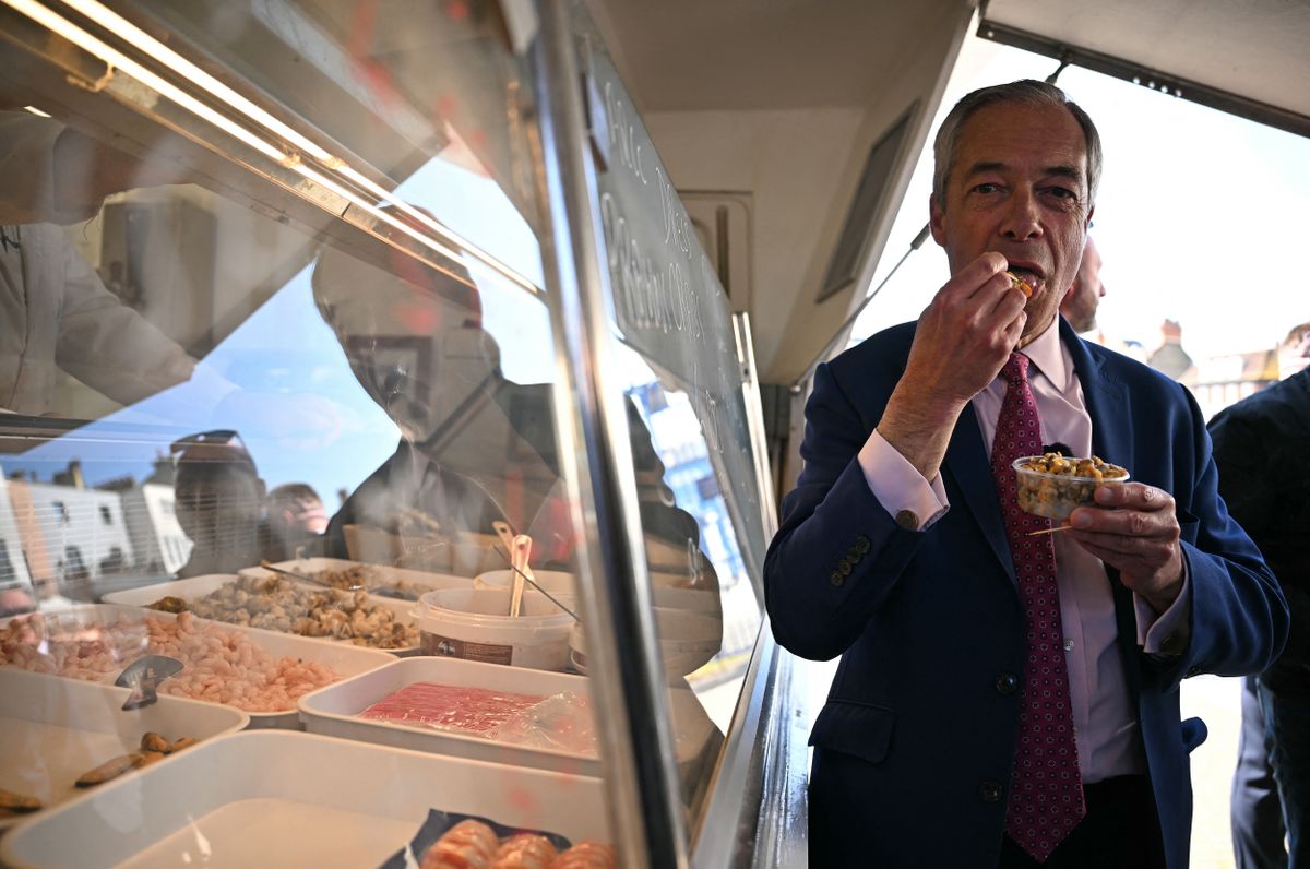 Reform UK Leader Nigel Farage eats a portion of cockles as he poses for a photograph after visiting a seafood stall whilst canvassing for voters ahead of local elections, in Ramsgate on the south east coast of England, on April 24, 2025. (Photo by Ben STANSALL / AFP)