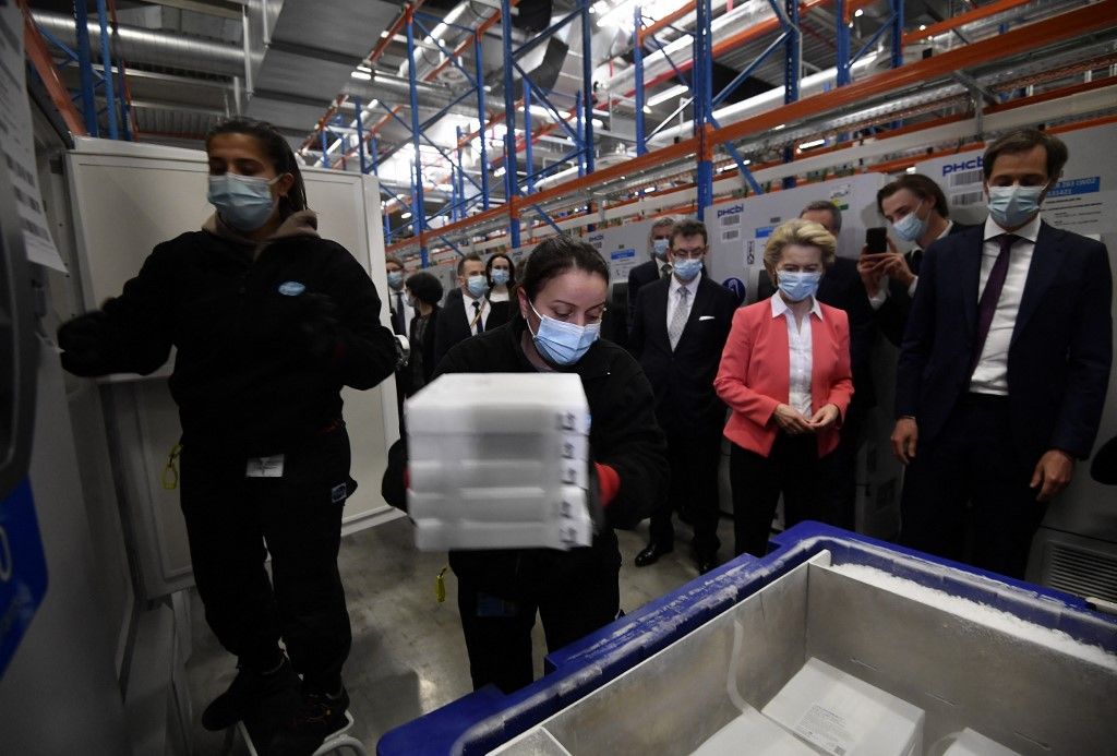 European Commission President Ursula von der Leyen (C) Pfizer CEO Albert Bourla (L), Belgium's Prime Minister Alexander De Croo (R) watch workers moving boxes of vaccines from a freezer during a visit at the factory of US pharmaceutical company Pfizer, in Puurs, on April 23, 2021. (Photo by JOHN THYS / POOL / AFP)