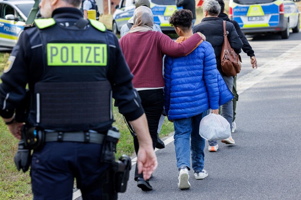(FILES) Officers of the German Federal Police (Bundespolizei) escort a group of migrants near Forst, eastern Germany on October 11, 2023, during a patrol near the border with Poland. Germany's new government on Wednesday said that it would reject most asylum seekers at its borders as conservative Chancellor Friedrich Merz seeks to limit irregular immigration and curb the rise of the far-right. The move is a key part of Merz's plans to wrest the initiative away from the anti-immigration Alternative for Germany (AfD), which came second in February's general election and has continued to climb in the polls. (Photo by JENS SCHLUETER / AFP)
