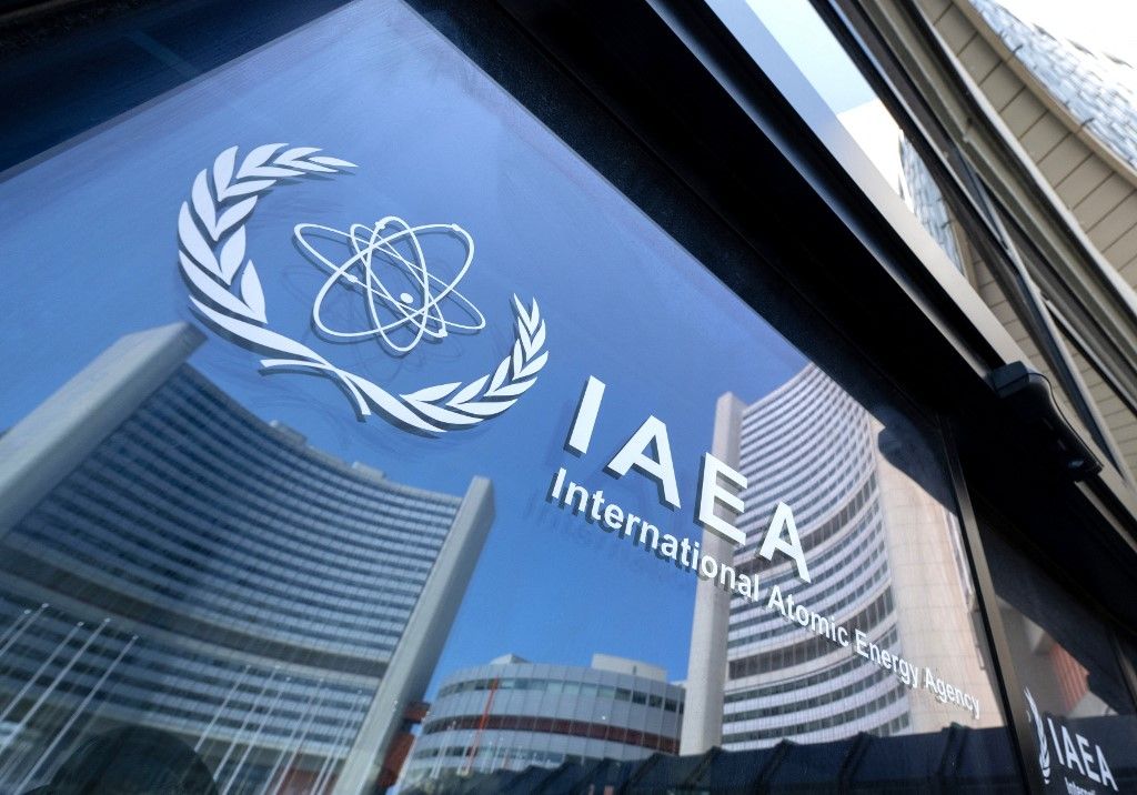 Buildings of the International Atomic Energy Agency (IAEA) headquarters reflect in doors with the agency's logo during the IAEAs Board of Governors meeting in Vienna, Austria on June 13, 2025, where the IAEAs head Rafael Grossi briefed board members following Israeli strikes on Iran, including on the Natanz uranium enrichment facility. (Photo by Joe Klamar / AFP)