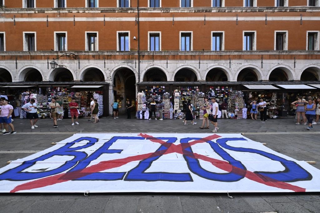 People gather to protest against the wedding of Amazon Founder and CEO Jeff Bezos and journalist Lauren Sanchez in Venice, on June 13, 2025. Poster campaigns and stickers have spread throughout the city, including one with images of Bezos reading "No space for Bezos" as some local residents protest claiming the city is transformed into a playground for billionaires. (Photo by ANDREA PATTARO / AFP)