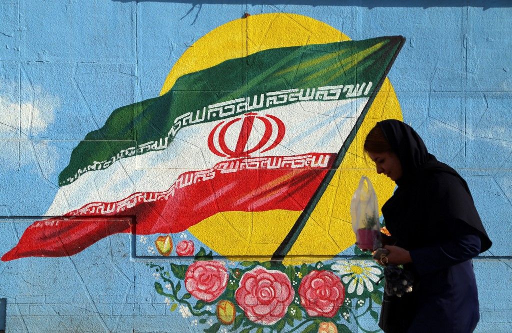TEHRAN, IRAN - JANUARY 16 : A Iranian woman walks past a wall painting in the shape of Iranian flag in Tehran, Iran on the first anniversary of nuclear deal between Iran and world powers on January 16, 2017. Media reported that Iran is to complete its last steps in an underground nuclear facility in Fordo on the one year anniversary of the implementation of the landmark nuclear deal between Iran and world powers. Fatemeh Bahrami / Anadolu Agency (Photo by Fatemeh Bahrami / ANADOLU AGENCY / Anadolu via AFP)