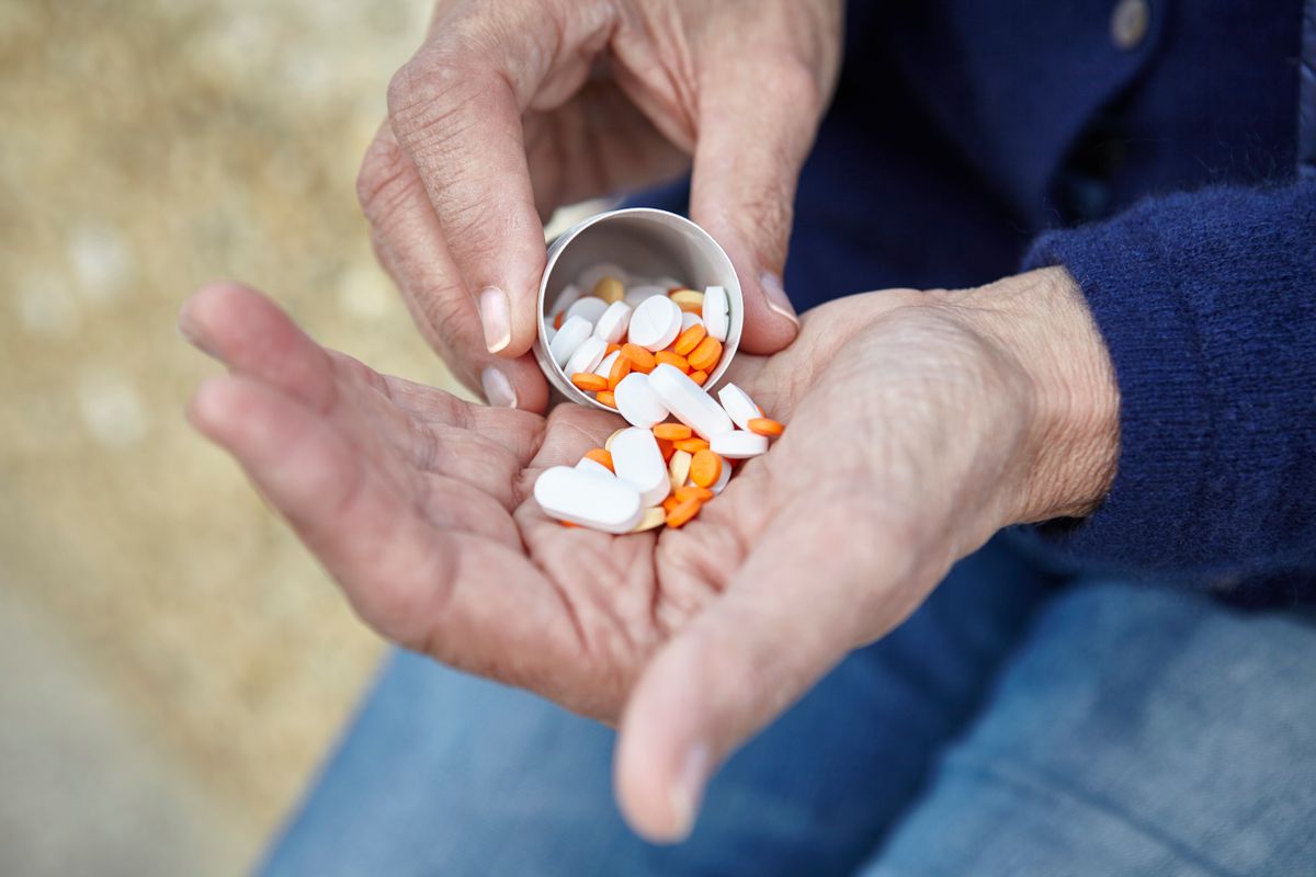 Woman dispensing pills from pill bottle into hand