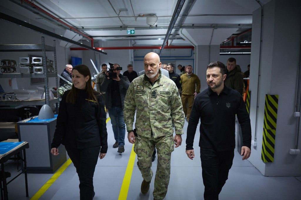 This handout photograph taken and released by Ukrainian Presidential Press Service on February 8, 2025, shows Ukrainian President Volodymyr Zelensky (R) and the Chair of the NATO Military Committee Giuseppe Cavo Dragone (C) during their during a visit to a defense industry enterprise, in an undisclosed location in Ukraine. President Volodymyr Zelensky met with the Chair of the NATO Military Committee, Giuseppe Cavo Dragone, who made his first foreign visit in this position specifically to Ukraine. At one of the defense industry enterprises, they got acquainted with the production capacities and characteristics of Ukrainian long-range weapons and spoke with the people working there. (Photo by Handout / UKRAINIAN PRESIDENTIAL PRESS SERVICE / AFP) / RESTRICTED TO EDITORIAL USE - MANDATORY CREDIT "AFP PHOTO / Ukrainian Presidential Press Service" - NO MARKETING NO ADVERTISING CAMPAIGNS - DISTRIBUTED AS A SERVICE TO CLIENTS