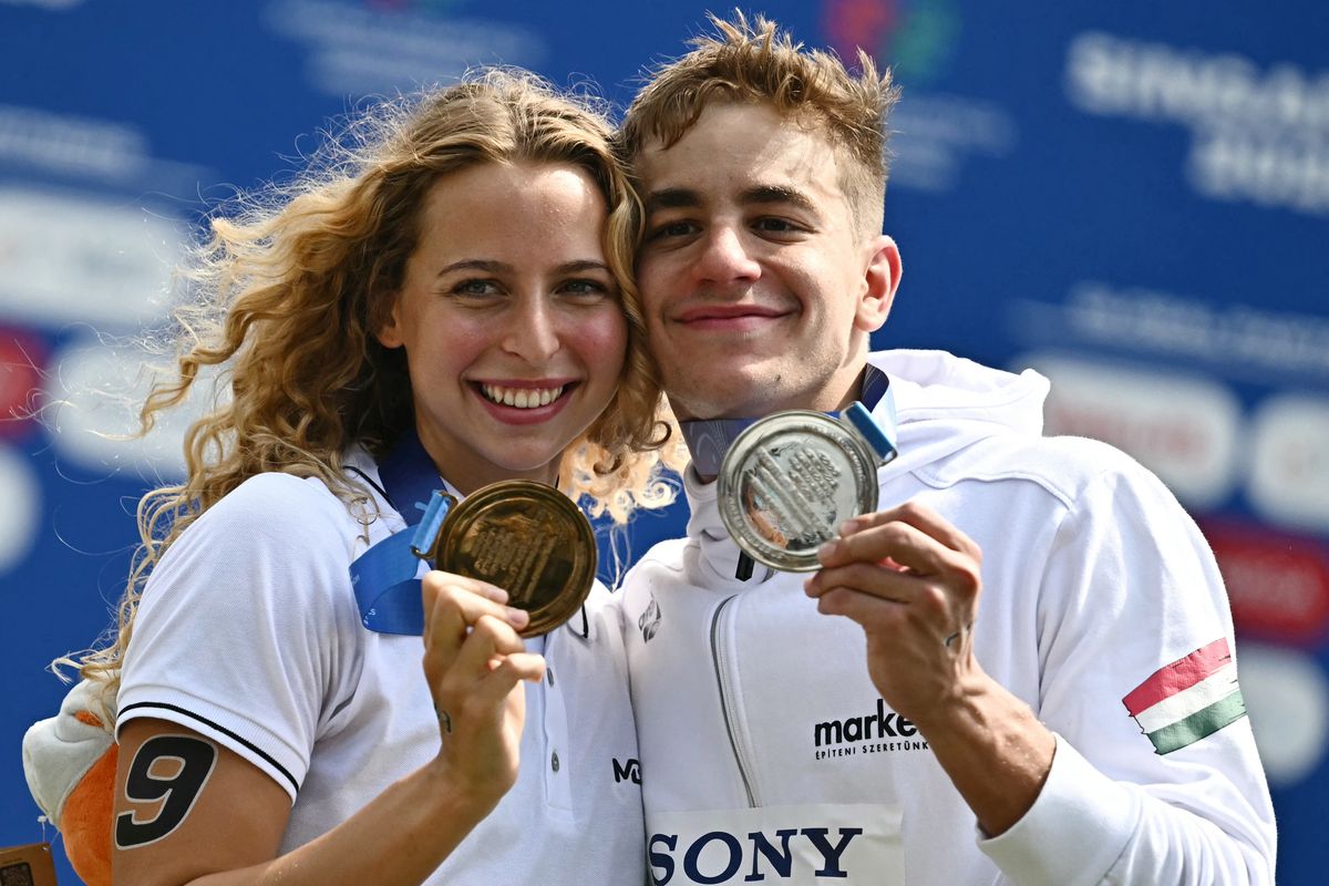 Hungary's swimmer Bettina Fabian (L), who finished third in the women's 3km knockout sprint open water swimming event, poses with compatriot David Betlehem, who finished second in the men's 3km knockout sprint open water swimming event, pose with their medals following the presentation ceremonies during the 2025 World Aquatics Championships at Sentosa Island in Singapore on July 19, 2025. (Photo by MANAN VATSYAYANA / AFP)