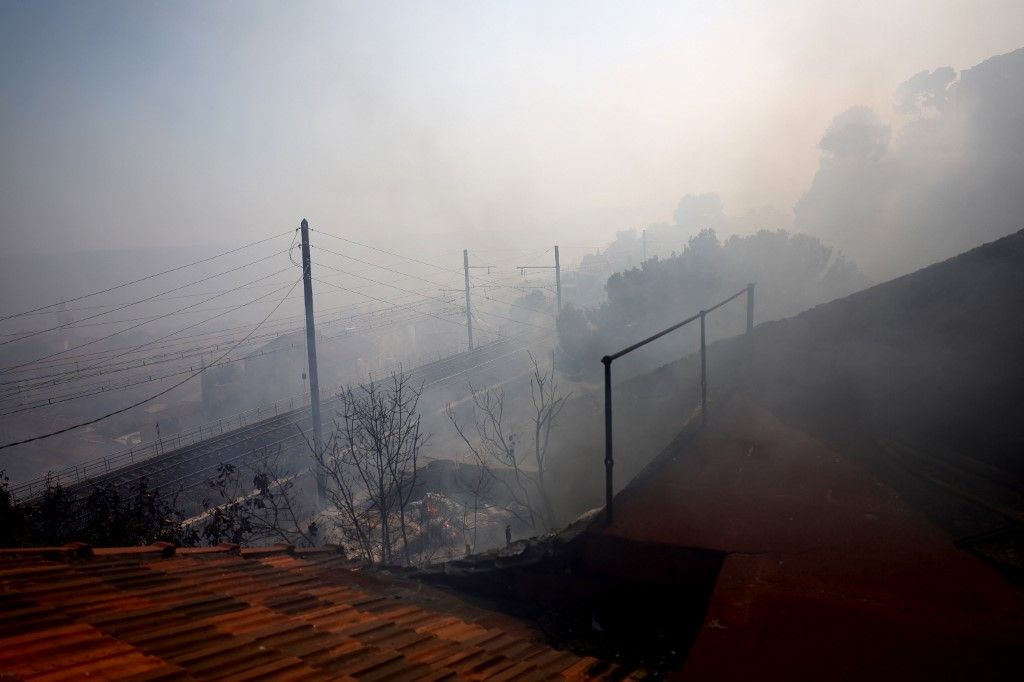 Smoke billows in L'Estaque district of Marseille, southern France on July 8, 2025, following a wildfire. A wildfire in southern France on July 8 forced Marseille airport to close and interrupted train traffic as the blaze spread rapidly to the edges of the southern French city. Several forest fires have raged in recent days in southern France, fanning out at speed due to wind and parched vegetation after a heatwave. (Photo by Clement MAHOUDEAU / AFP)