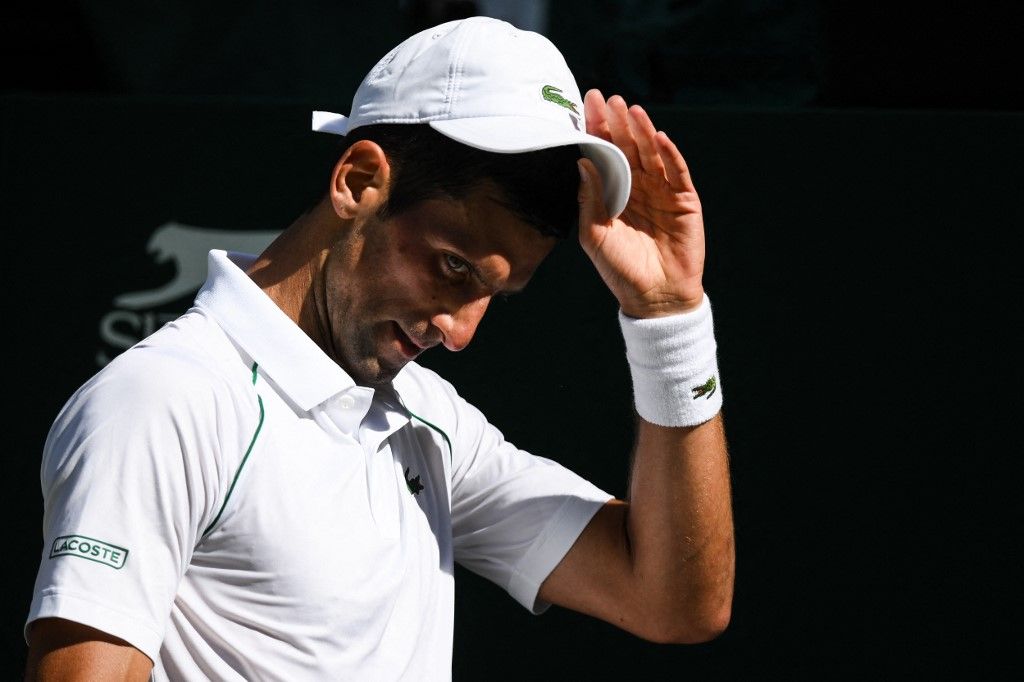 Serbia's Novak Djokovic fits his cap as he plays against Britain's Cameron Norrie during their men's singles semi final tennis match on the twelfth day of the 2022 Wimbledon Championships at The All England Tennis Club in Wimbledon, southwest London, on July 8, 2022. (Photo by Daniel LEAL / AFP) / RESTRICTED TO EDITORIAL USE