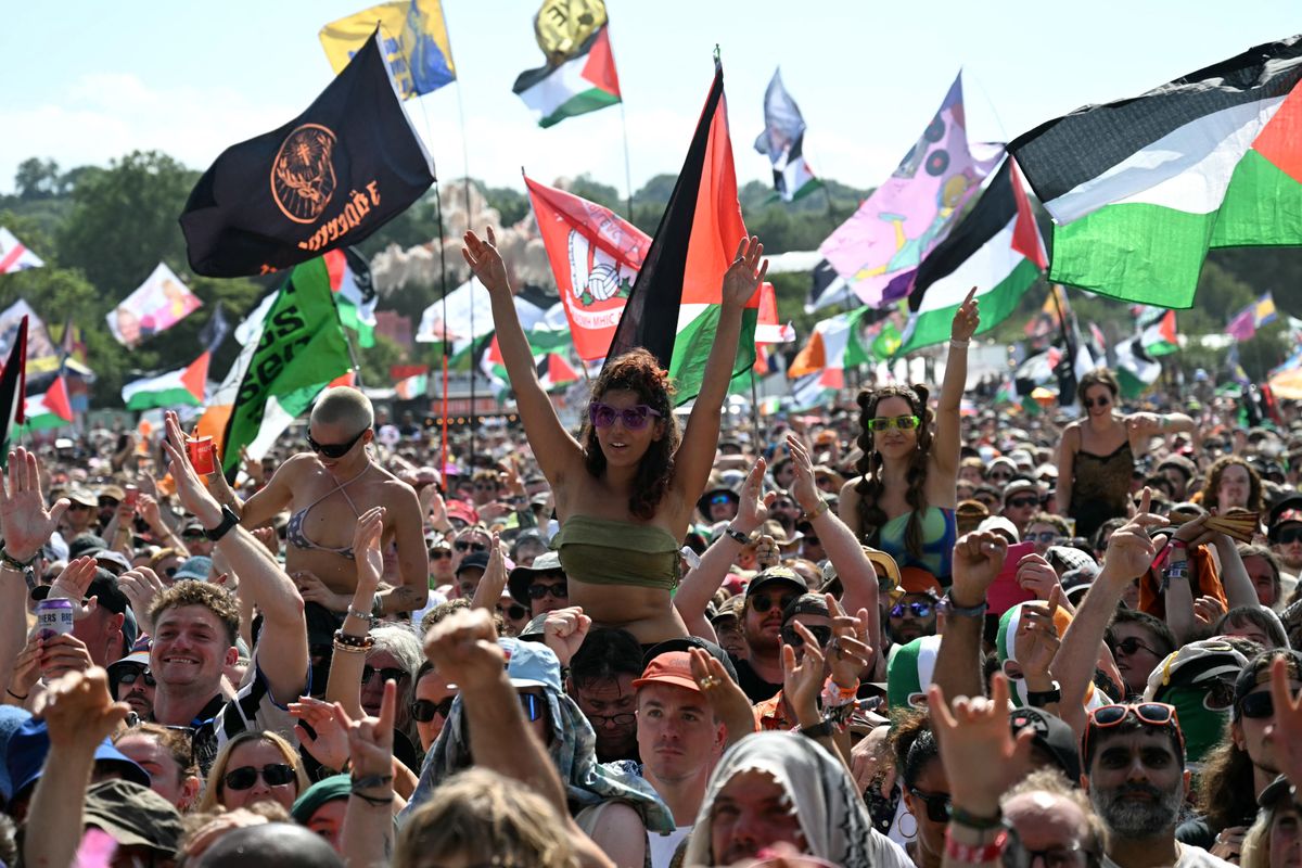 Festivalgoers watch as Irish rap band Kneecap perform at the West Holts stage on the fourth day of the Glastonbury festival at Worthy Farm in the village of Pilton in Somerset, south-west England, on June 28, 2025. (Photo by Oli SCARFF / AFP)