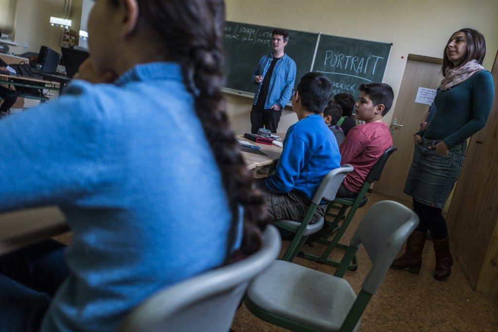 Syrian teaching assistant Hend Al Khabbaz (R) coaches young Syrian refugee pupils during class at the Sigmund-Jaehn-Grundschule (primary school) in Fuerstenwalde, eastern Germany, on January 19, 2018. Al Khabbaz, an English teacher in her native Homs, came to Germany as a refugee in 2015, completed her training as a teacher in Potsdam, and is now teaching at the Sigmund Jaehn school, focusing particularly on young students whose mother tongue is not German. (Photo by John MACDOUGALL / AFP) / TO GO WITH AFP STORY by Yannick PASQUET