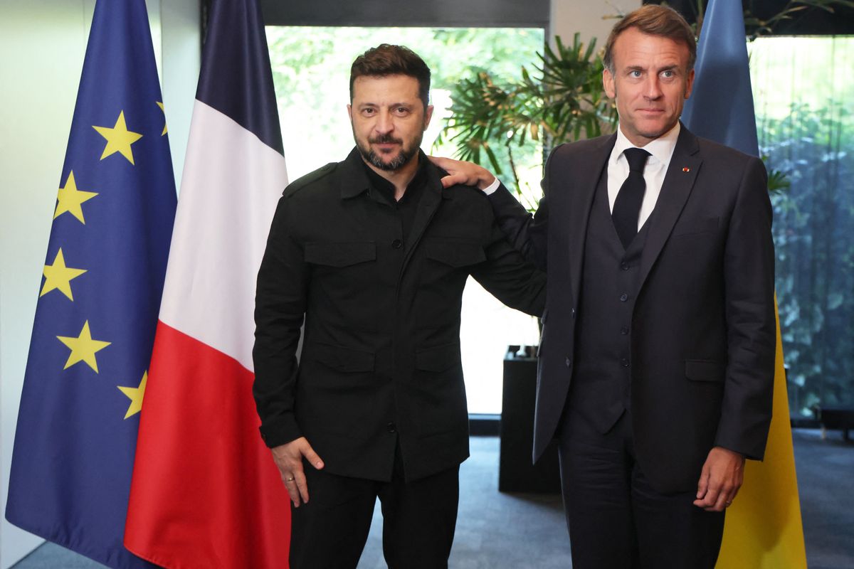 Ukraine's President Volodymyr Zelensky (L) and France's President Emmanuel Macron react as they meet on the sidelines of the two-day NATO's Heads of State and Government summit in The Hague on June 24, 2025. (Photo by Ludovic MARIN / POOL / AFP)