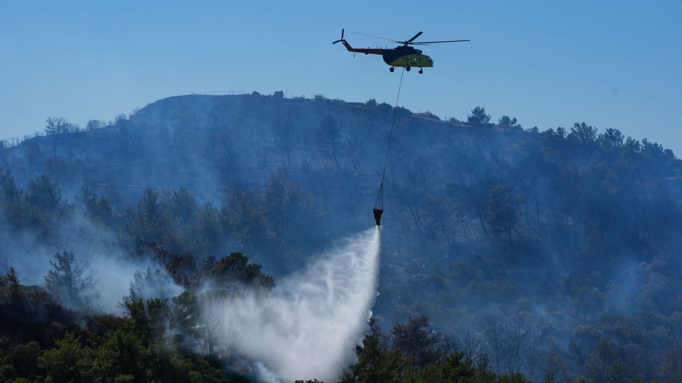 Egy helikopterről oltják a lángoló erdőt Törökországban.