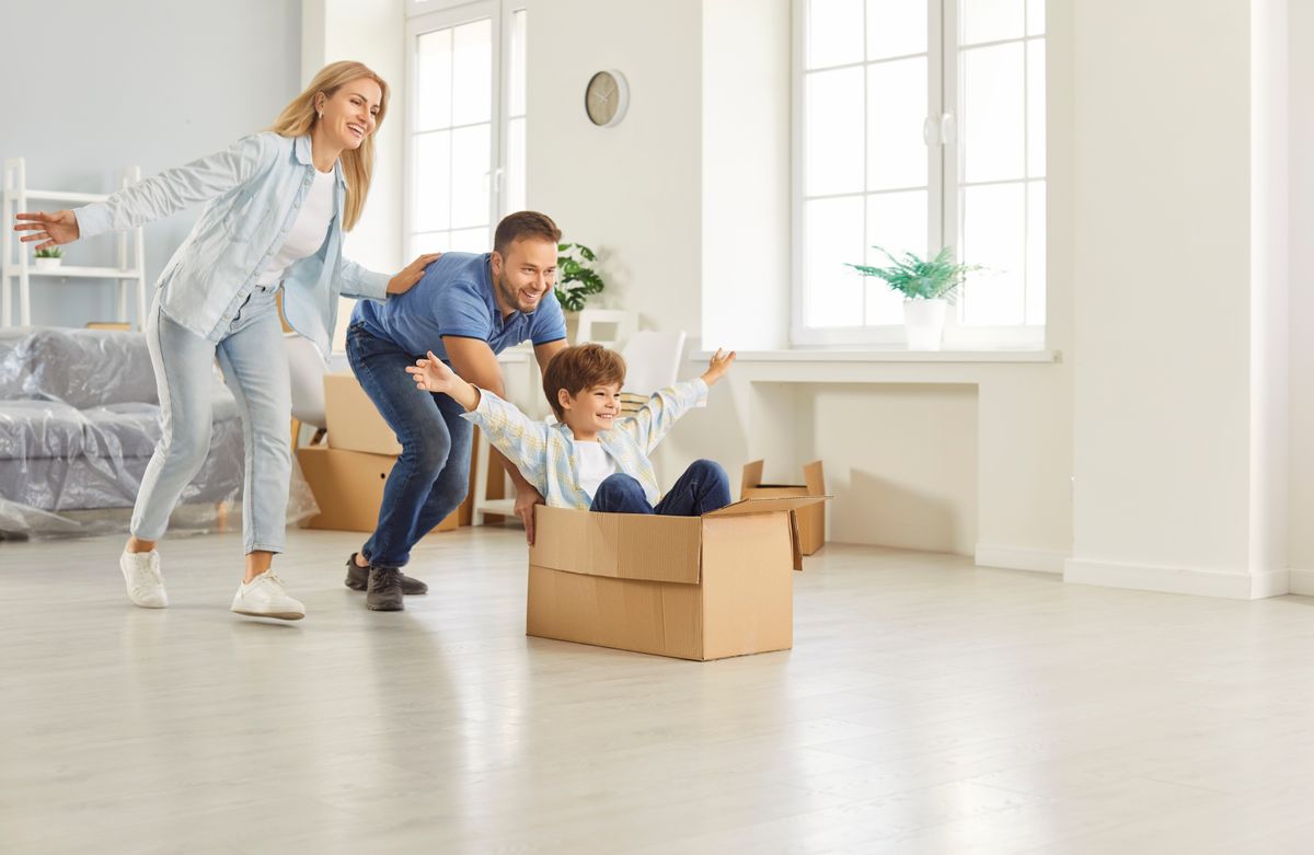 Happy family, new flat home owners, parents playing with cute small kid son on moving day, tenants, renters homeowners and child having fun riding in cardboard 
box in living room, relocating

új lakás gyerekkel