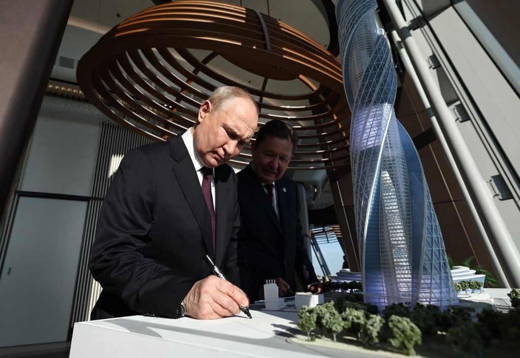 In this pool photograph distributed by Russian state agency Sputnik, Russia's President Vladimir Putin (L) signs a mock up, flanked by Russia's energy giant Gazprom CEO Alexei Miller as they visit the Lakhta Centre skyscraper, the headquarters of Russian gas monopoly Gazprom in Saint Petersburg on June 5, 2024. (Photo by Alexander KAZAKOV / POOL / AFP)
