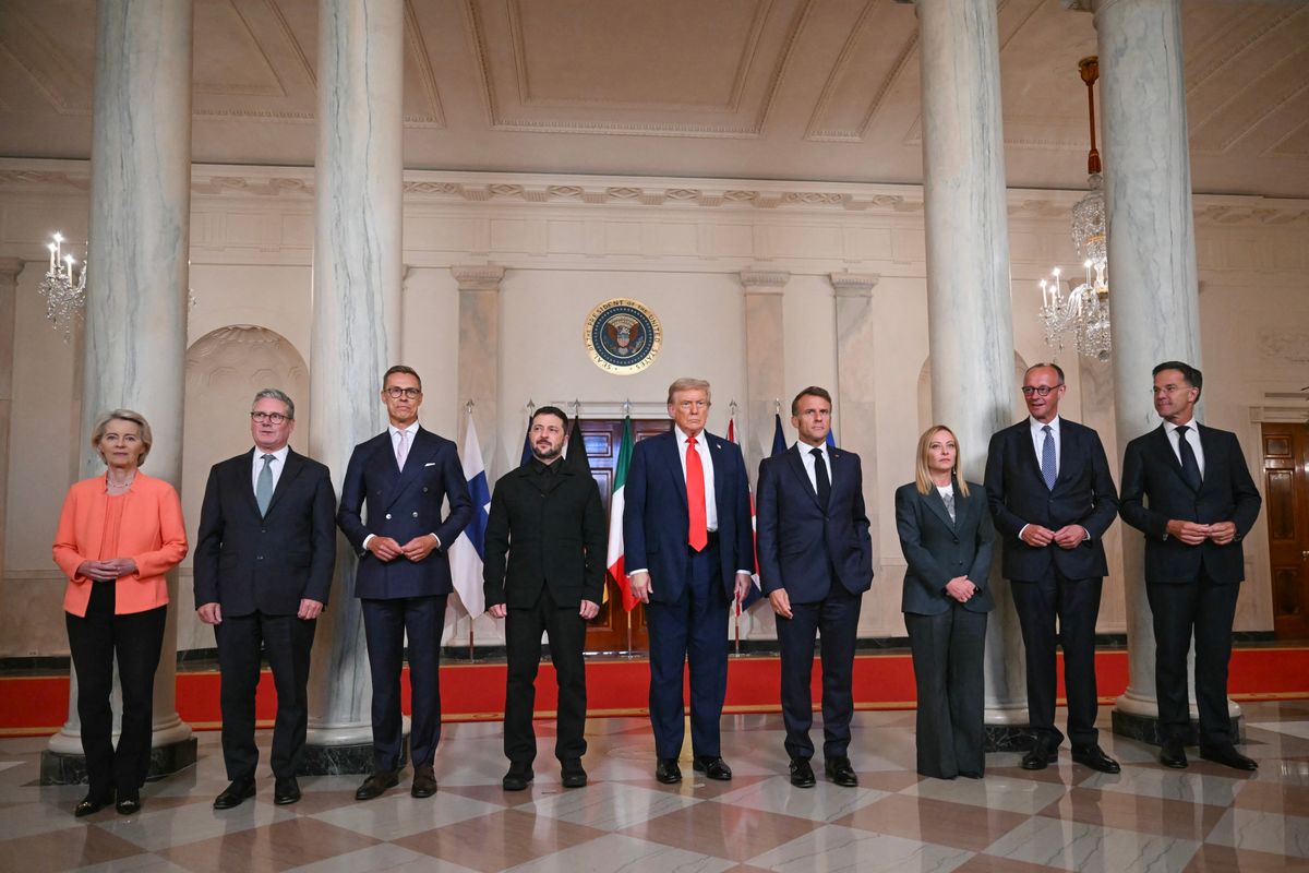 (L/R) European Commission President Ursula von der Leyen, British Prime Minister Keir Starmer, Finnish President Alexander Stubb, Ukrainian President Volodymyr Zelensky, US President Donald Trump, French President Emmanuel Macron, Italian Prime Minister Giorgia Meloni, German Chancellor Friedrich Merz and NATO Secretary-General Mark Rutte pose for a family photo in the Cross Hall of the White House in Washington, DC, on August 18, 2025. European leaders join Ukrainian President Volodymyr Zelensky in talks with US President Donald Trump on August 18, as they try to find a way to end Russia's offensive.  The leaders heading to Washington on Monday to appear alongside Zelensky call themselves the "coalition of the willing." (Photo by ANDREW CABALLERO-REYNOLDS / AFP)