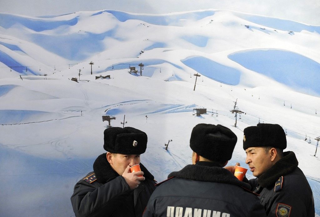 Kazakh policemen drink hot coffee after the awarding ceremony for the men's and women's alpine skiing downhill event of the 7th Asian Winter Games at Shymbulak Alpine Sport Resort in Almaty on January 31, 2011. AFP PHOTO / LIU Jin (Photo by LIU JIN / AFP)