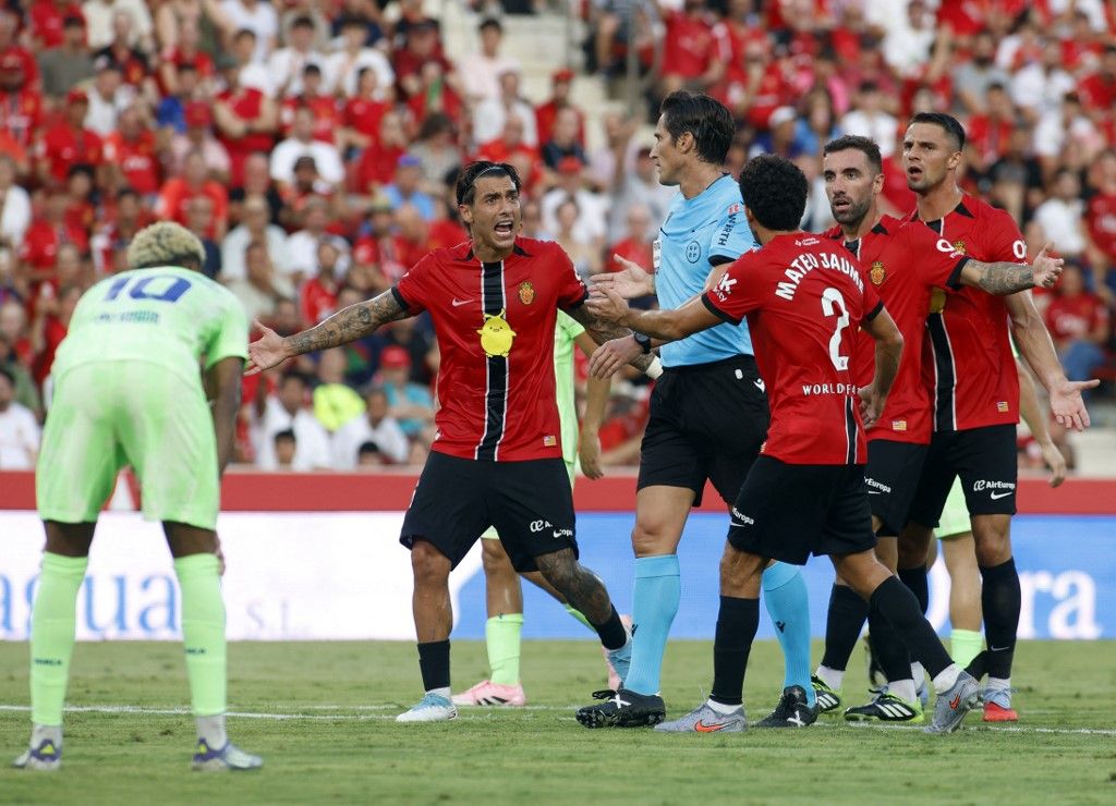 Real Mallorca players remonstrate with Spanish referee Jose Luis Munuera Montero during the Spanish league football match between RCD Mallorca and FC Barcelona at Mallorca Son Moix Stadium in Palma de Mallorca on August 16, 2025. (Photo by JAIME REINA / AFP)