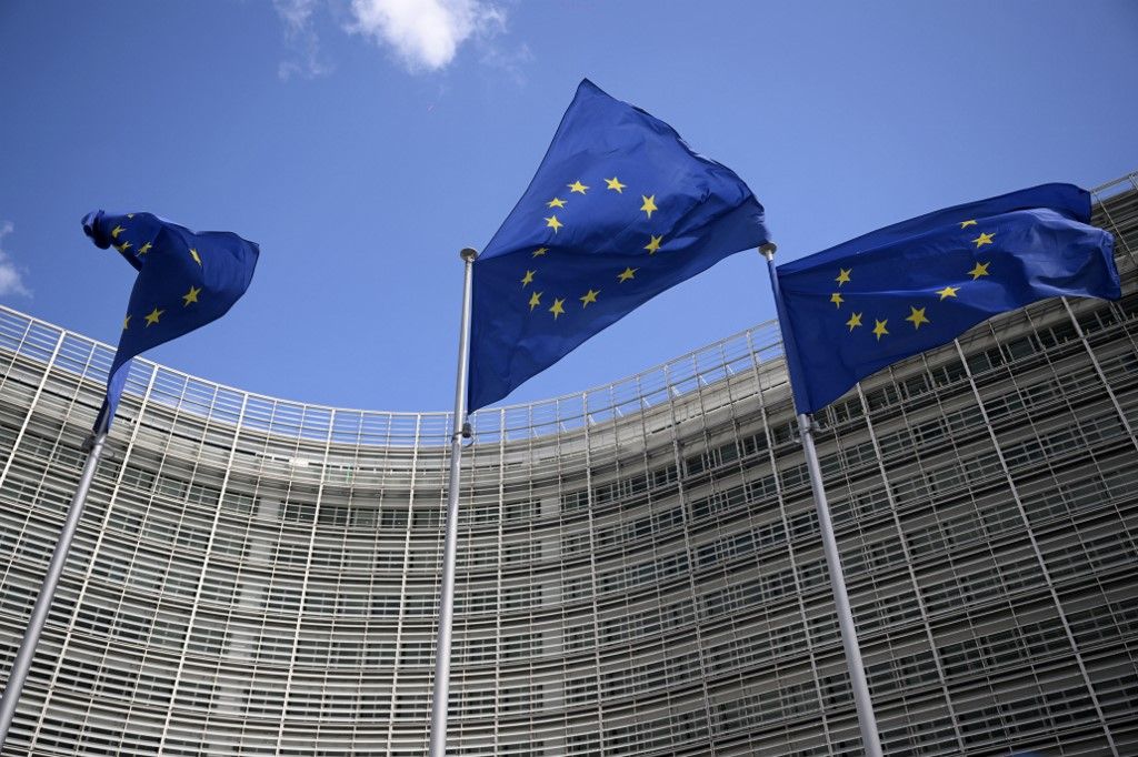 This photograph shows European flags floating outside the EU headquarters in Brussels, on May 28, 2025. (Photo by Nicolas TUCAT / AFP)