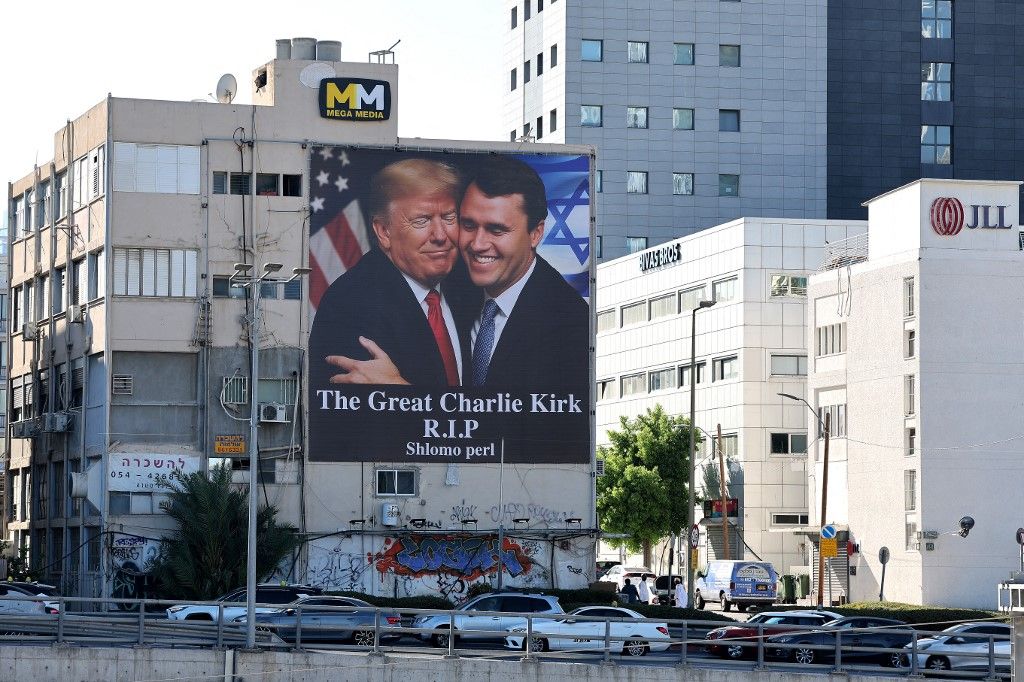 A billboard showing an image of US President Donald Trump (L) embracing US prominent right-wing activist Charlie Kirk, who was hit by a single bullet while addressing a large crowd at Utah Valley University in the town of Orem on September 10, hangs on the side of a building in Tel Aviv, on September 13, 2025. Trump on September 12, announced that the suspect had been taken into custody over the killing of right-wing activist Charlie Kirk after a massive manhunt. (Photo by Jack GUEZ / AFP)
