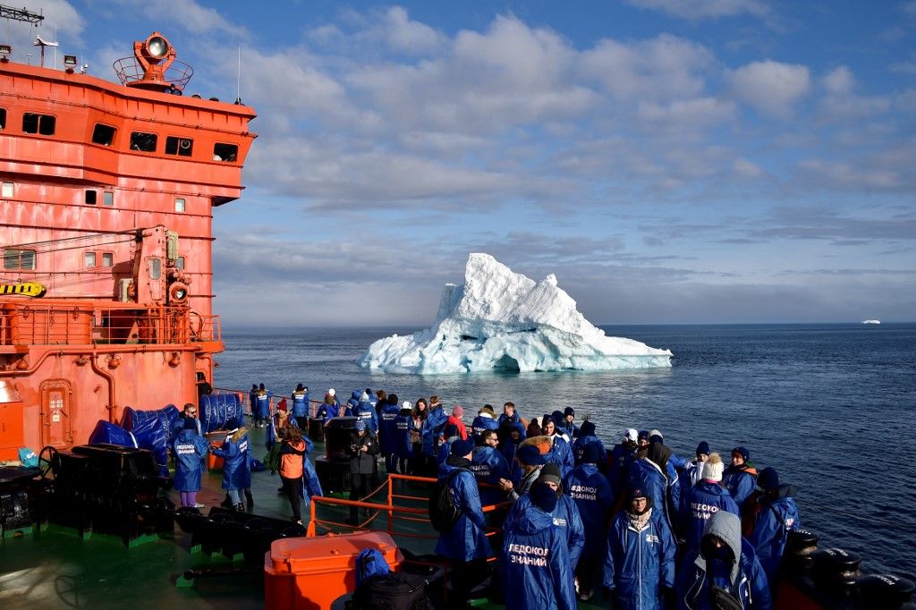 Russian teenagers who won a contest to travel aboard the Russian "50 Years of Victory" nuclear-powered icebreaker look at an iceberg in the Arctic Ocean from the deck of the 160-metre (525-foot) ship on August 20, 2021. (Photo by Ekaterina ANISIMOVA / AFP)