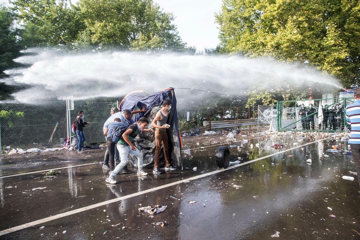 Magyar rendőrök vízágyúval próválják oszlatni a röszkei határátkelőnél támadó migránsokat 2015. szeptember 16-án (Fotó: Kurucz Árpád)