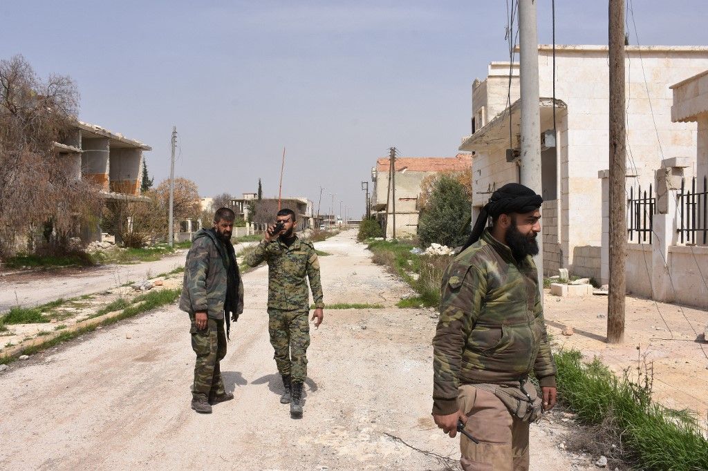 Syrian government forces walk in Deir Hafer on the eastern outskirts of Aleppo on March 30, 2017, after they took control of the town from Islamic State (IS) group fighters. (Photo by George OURFALIAN / AFP)
