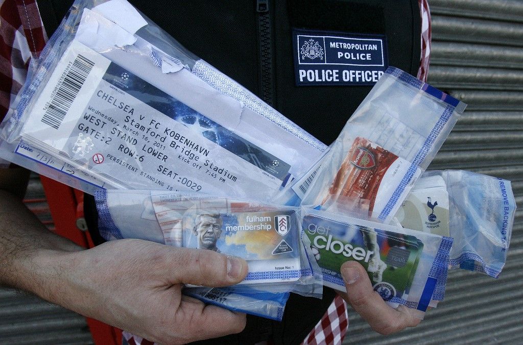 A police officer poses for photographs with English Premier League soccer club membership cards and UEFA Champions League match tickets recovered from a suspected ticket tout, during a search of a furniture shop in south London, on March 8, 2011. London police said they arrested five people Tuesday in a crackdown on touts before tickets for the 2012 Olympics go on sale. The five men and one woman, ranging from 25 to 57 years old, were arrested in a string of dawn raids in London and in Dorset in southwest England. AFP PHOTO/Akira Suemori/POOL (Photo by AKIRA SUEMORI / POOL / AFP)