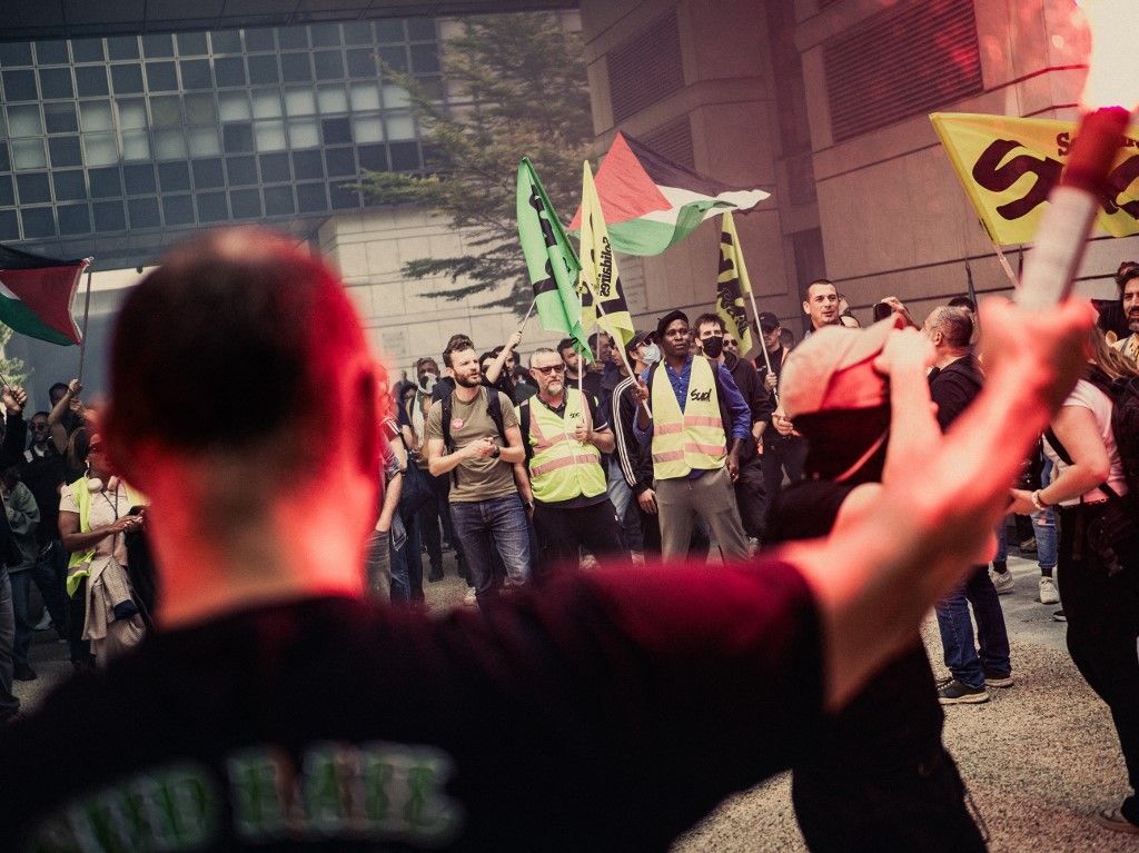 A person with a smoke bomb in front of protesters with flags during an action at the Ministry of Economy and Finance in Bercy led by the SUD Rail union as part of a day of strikes and national demonstrations called by the unions against France s national budget in Paris France on September 18, 2025. (Photo by Bastien Ohier / Hans Lucas via AFP)