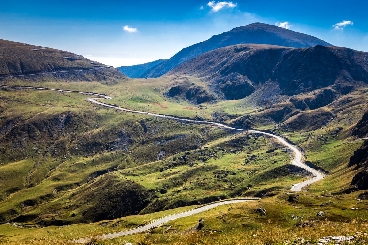Transalpina

Wide angle color image depicting a scene in the stunning Carpathian mountains of Romania. A winding road twists and turns through the dramatic mountainous landscape, which is offset by a dazzling blue sky and cloudscape. Room for copy space.