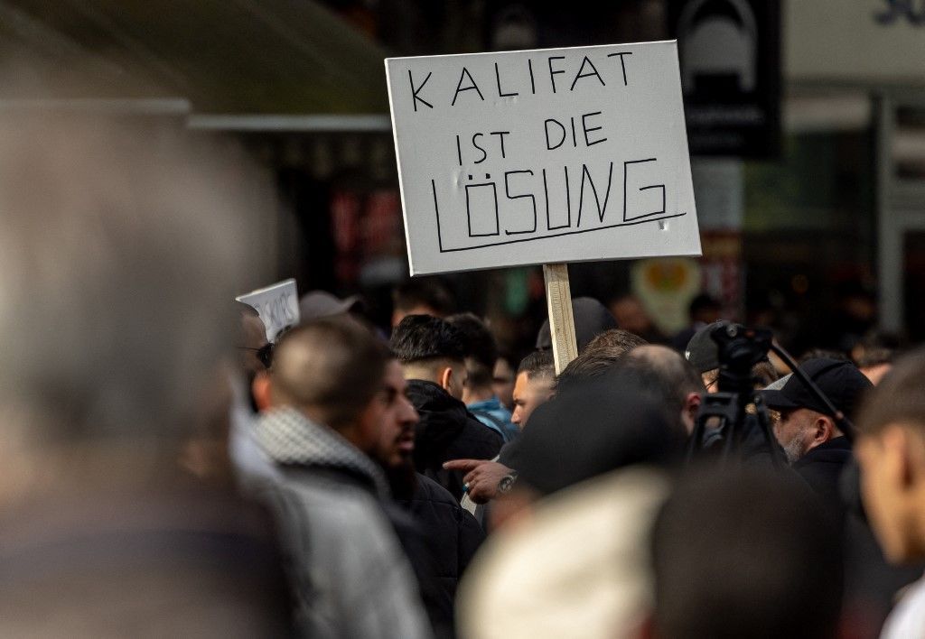 27 April 2024, Hamburg: Participants in an Islamist demonstration hold up a poster with the slogan "Caliphate is the solution". Photo: Axel Heimken/dpa (Photo by AXEL HEIMKEN / dpa Picture-Alliance via AFP)