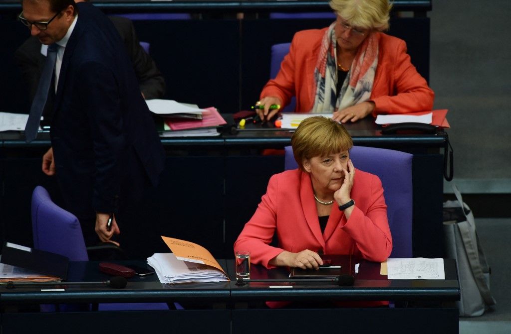 German Chancellor Angela Merkel (R) sits as German Transport Minister Alexander Dobrindt takes his seat at the Bundestag, the lower house of parliament in Berlin on September 24, 2015. Merkel said that a European Union deal to relocate 120,000 refugees was far from what was necessary to resolve the biggest migrant crisis facing the region since World War II. AFP PHOTO / JOHN MACDOUGALL (Photo by JOHN MACDOUGALL / AFP)