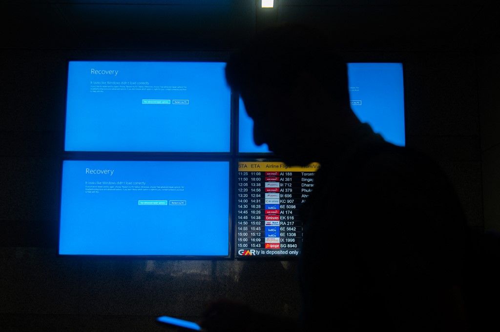 People are moving past screens displaying error messages amid a global Microsoft outage at the Indira Gandhi International (IGI) Airport, in New Delhi, India, on July 19, 2024. Airlines, businesses, and various institutions are being affected due to the global Microsoft outage. Various flights around the world are being canceled, and flight operations that rely on Microsoft systems are being affected. (Photo by Kabir Jhangiani/NurPhoto) (Photo by Kabir Jhangiani / NurPhoto via AFP)