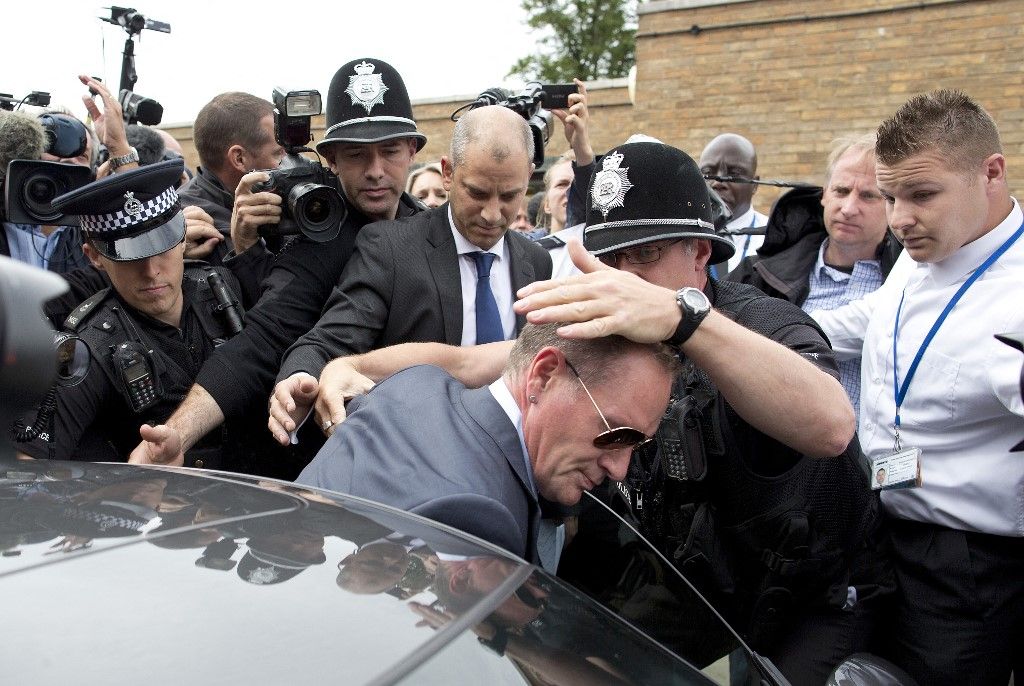 Former England footballer Paul Gascoigne (C) is assisted by police officers as he leaves Stevenage Magistrates Court, north of London, on August 5, 2013. Troubled former England football star Paul Gascoigne was fined after pleading guilty Monday to common assault and drunk and disorderly behaviour at a railway station.  AFP PHOTO / JUSTIN TALLIS (Photo by JUSTIN TALLIS / AFP)