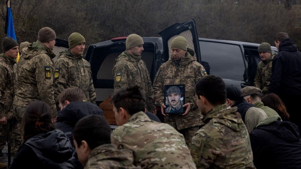 A soldier holds a photo of Ukrainian serviceman and Hospitallers Oleksandr Oliinyk, callsign "Bohush" during the funeral ceremony in Kyiv on March 25, 2025, amid the Russian invasion of Ukraine. (Photo by Tetiana DZHAFAROVA / AFP)