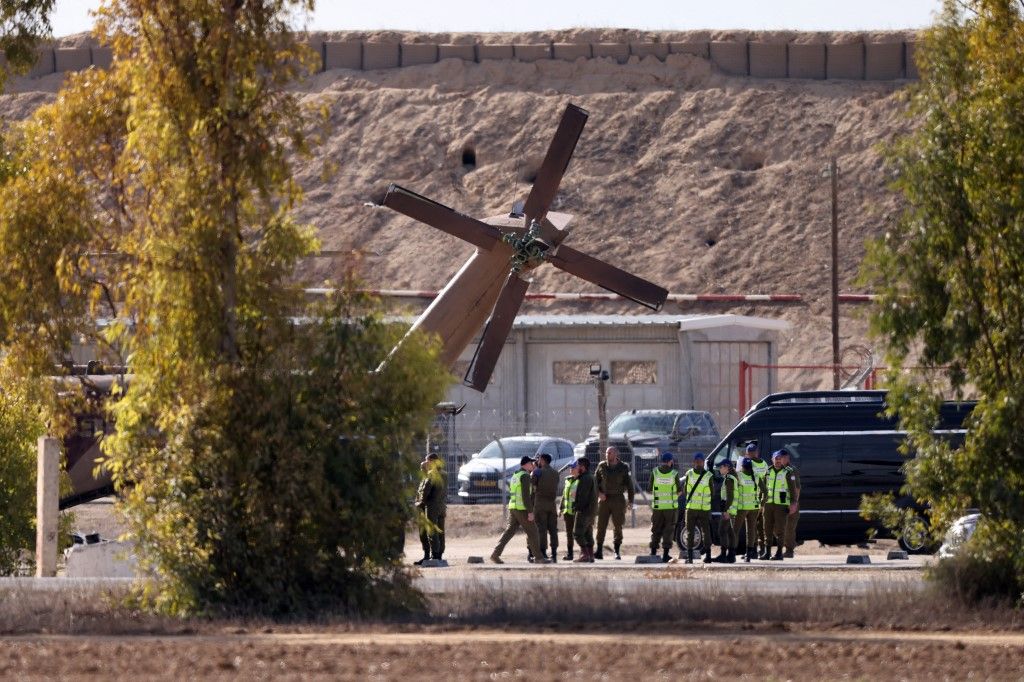 Egy izraeli katonai helikopter készül fogadni a négy újonnan szabadon engedett izraeli túszot, akiket egy furgonban szállítanak (Fotó: MENAHEM KAHANA / AFP)