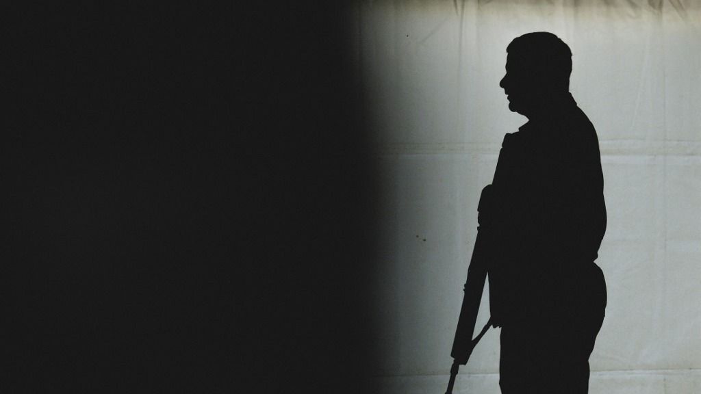 A soldier stands with a G36 rifle, photographed as a silhouette in the temporarily erected Convoy Support Center at the Oberlausitz military training area near Weisskeissel, September 6, 2025. In September, a civilian-operated rest and assembly area for a military deployment will be set up at the Oberlausitz military training area. Army forces are moving through Germany via Poland to Lithuania as part of the Grand Eagle sub-exercise, which is part of the Quadriga 2025 exercise cluster. Along the way, they will be supplied at the Convoy Support Center (CSC), which is operated exclusively by Rheinmetall. (Photo by Florian Gaertner / Photothek Media Lab / dpa Picture-Alliance via AFP)