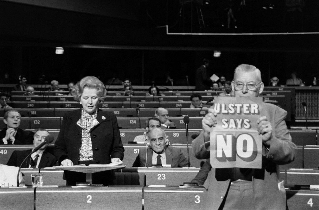 British Prime Minister Margaret Thatcher delivers a speech at the European Parliament, on December 09, 1986 in Strasbourg as the leader of the Democratic Unionist Party Reverend Ian Paisley (R) brandishes a placard saying "Ulster says no". (Photo by JEAN-CLAUDE DELMAS / AFP)
