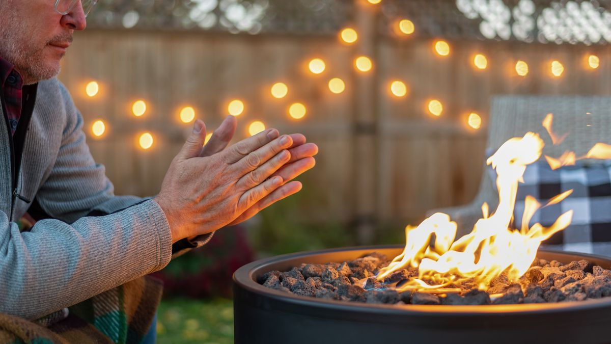 Man warming his hands by a fire at dusk