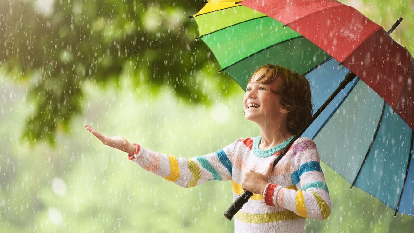 Child playing in autumn rain. Kid jumping in muddy puddle in beautiful park. Little boy with colorful umbrella under heavy fall shower. Stormy rainy weather fun időjárás