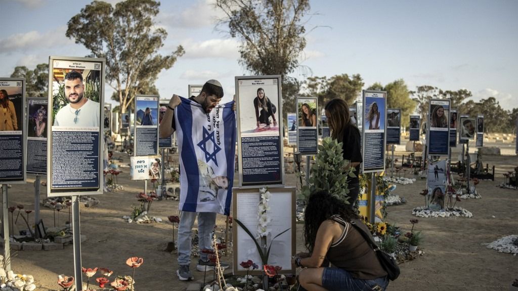 Family members of a victim of the 2023 October 7 attacks clean and decorate their memorial at the Nova Festival grounds in Reim in southern Israel on October 6, 2025, a day before the attacks' second anniversary. Hamas's October 2023 attack resulted in the deaths of 1,219 people, mostly civilians, according to an AFP tally of Israeli official figures. Palestinian militants also seized 251 hostages, 47 of whom are still in the Palestinian territory. Of those, the Israeli military says 25 are dead. (Photo by JOHN WESSELS / AFP)
