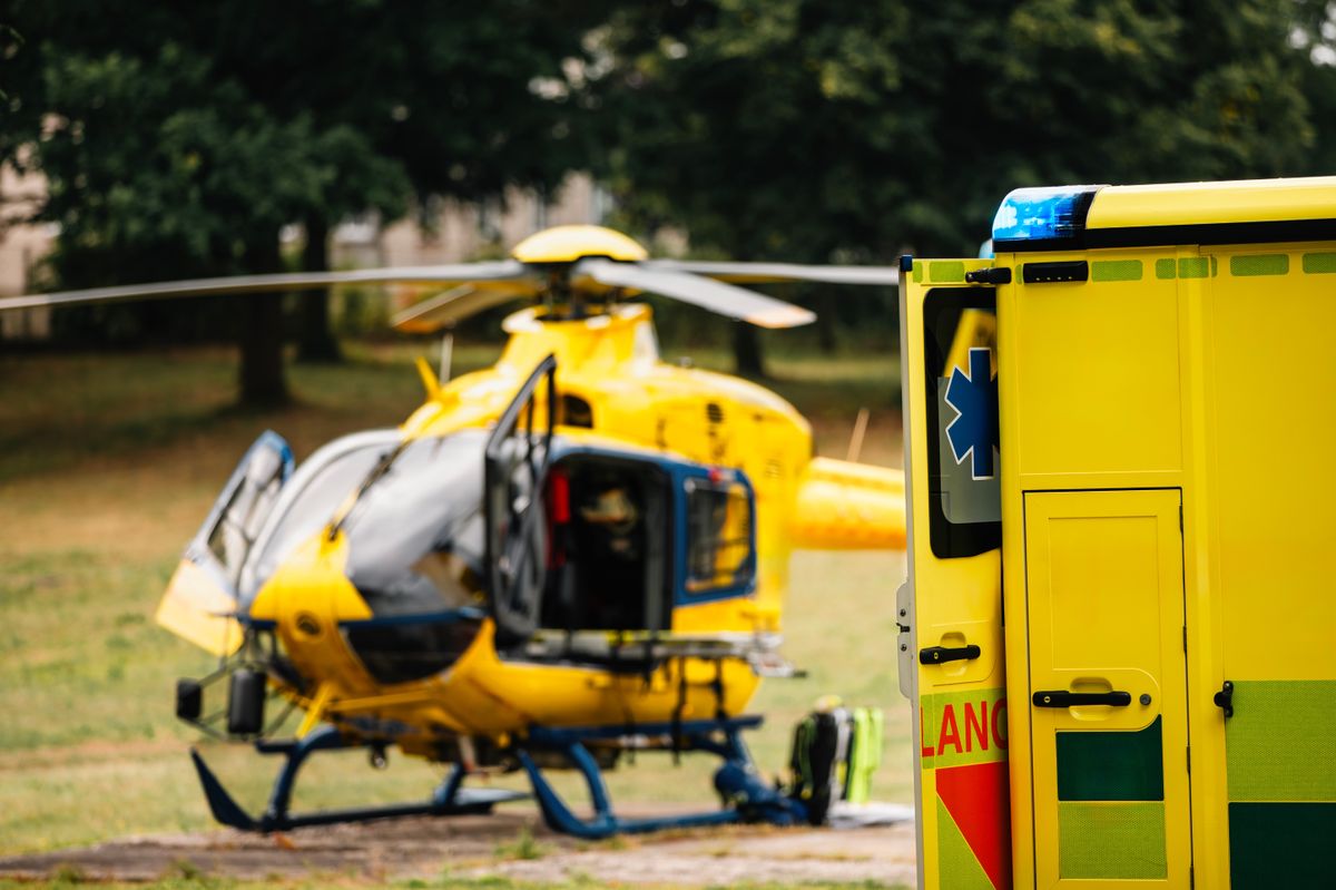 Selective focus on blue light flasher on ambulance car of emergency medical service against helicopter. Themes rescue, urgency and health care.