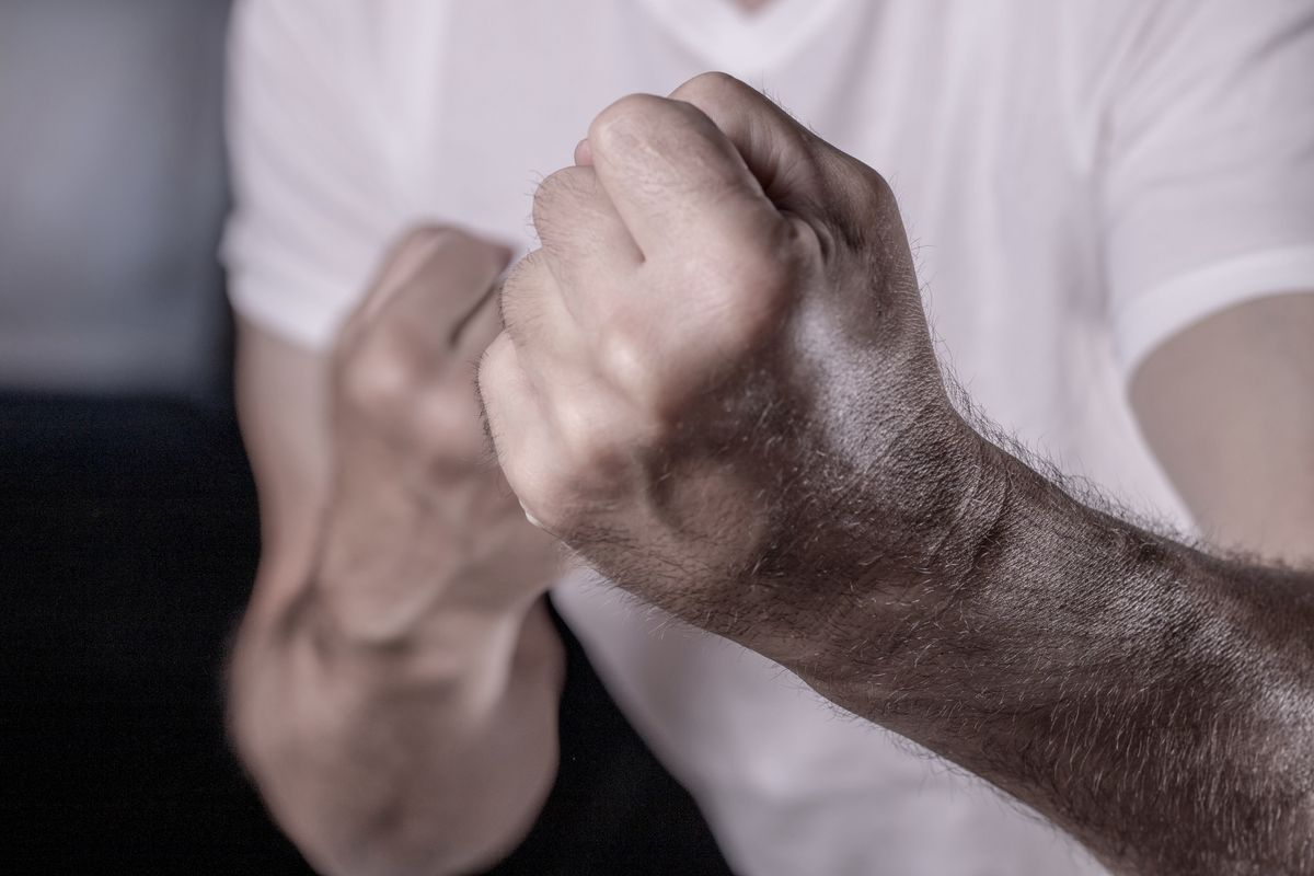 Boxing and self-defence. Side view of aggressive man with beard in white t-shirt keeping fists clenched, ready for fight.