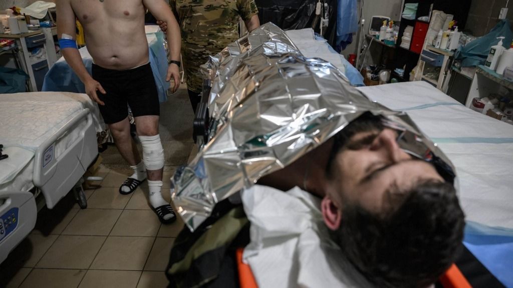 EDITORS NOTE: Graphic content / Medics attend to a Ukrainian soldier injured in a FPV drone strike, at a stabilisation point in an undisclosed location near the front line in the Donetsk region of eastern Ukraine on October 10, 2025, amid the Russian invasion of Ukraine. The soldier was travelling in an M113 armoured personnel carrier when itwas struck by a Russian FPV drone. (Photo by Ed JONES / AFP)