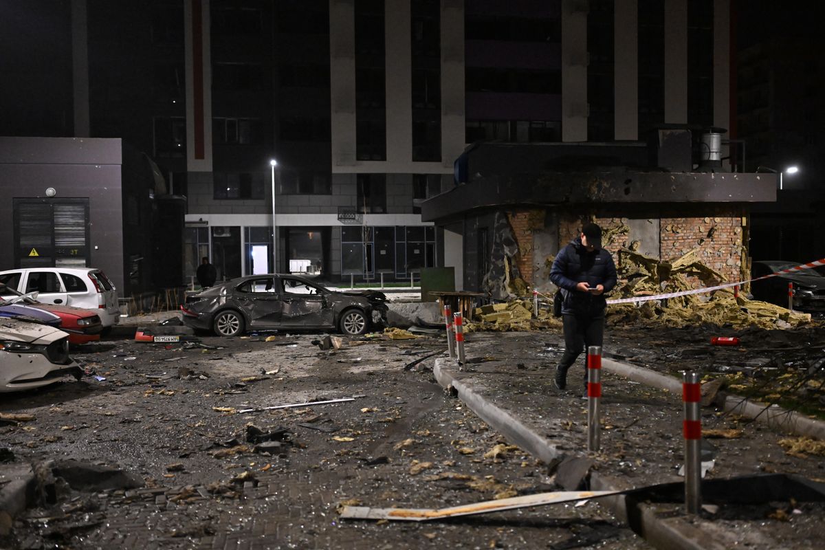A local resident walks among debris in the courtyard of a damaged residential building following a drone attack in Kyiv on November 29, 2025, amid the Russian invasion in Ukraine. A Russian drone attack targeted the Ukrainian capital in the early hours of November 29, 2025, wounding seven people, authorities in Kyiv said. (Photo by Sergei GAPON / AFP) Kijev