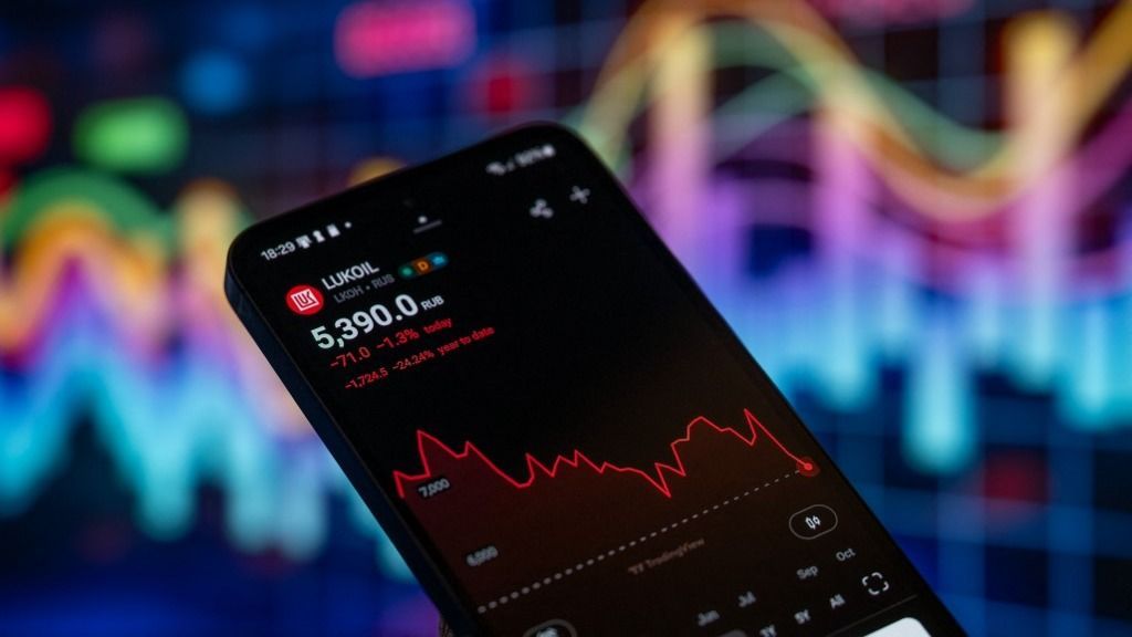 The Lukoil prize stock is displayed on a mobile phone with a financial stock graph seen in the background, in this photo illustration in Brussels, Belgium, on October 29, 2025. (Photo Illustration by Jonathan Raa/NurPhoto) (Photo by Jonathan Raa / NurPhoto via AFP)