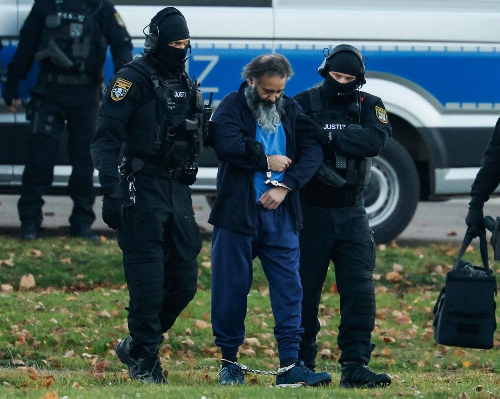 Judicial officers escort Saudi Arabian defendant Taleb Al Abdulmohsen towards a helicopter (unseen) after he left the temporary courthouse in Magdeburg, eastern Germany on November 10, 2025, after the opening of his trial over the deadly Magdeburg Christmas market attack in December 2024. The Saudi medical doctor is accused of driving an SUV through a Christmas market in a rampage in the eastern German city of Magdeburg on December 20, 2024. The attack killed a nine-year-old boy and five women aged between 45 and 75. He will face six counts of murder and 338 counts of attempted murder in a trial expected to last until at least March. Prosecutors charge that Abdulmohsen - a harsh critic of Islam and an adherent of far-right views and radical conspiracy theories - was motivated by "dissatisfaction and frustration". (Photo by Odd ANDERSEN / AFP)