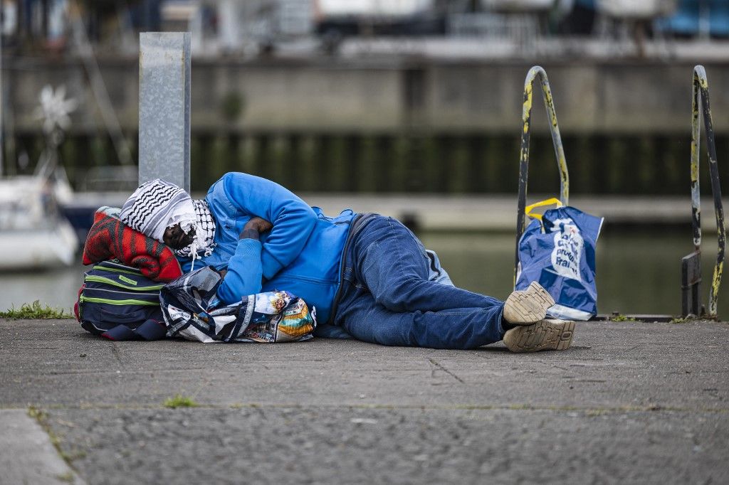 A migrant sleeps as he waits to board a bus heading to his departure point in Gravelines, northern France, on September 26, 2025. (Photo by Sameer Al-DOUMY / AFP)