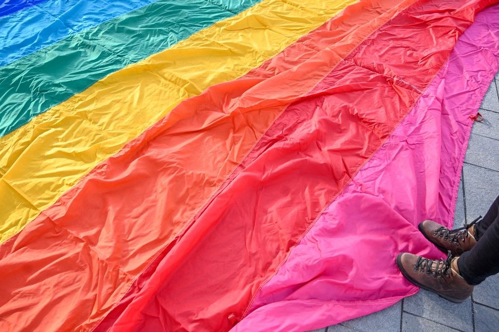 An LMBTQ activist stands on a 30-meter-long rainbow-colored flag displayed in front of the Hungarian Parliament building on January 21, 2022 prior to a press conference by Budapest Pride and European Pride Organizers Association (EPOA). Organizers announced that this year's Budapest Pride Parade will be held in the capital on July 23. Last year, Prime Minister Orban's government passed a law to ban the "promotion" of homosexuality to minors. The event's organizer Mate Hegedus said that the new regulation has made life difficult for all areas of the LGBTQ community and asks people eligible to vote to cast an invalid ballot for the LGBTQ referendum, which will be held at the same time as the parliamentary elections on April 3. (Photo by ATTILA KISBENEDEK / AFP)