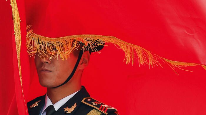 A Kínai Népi Hadsereg díszőrségének tagja zászlót tart VI. Fülöp spanyol király köszöntő ünnepségén